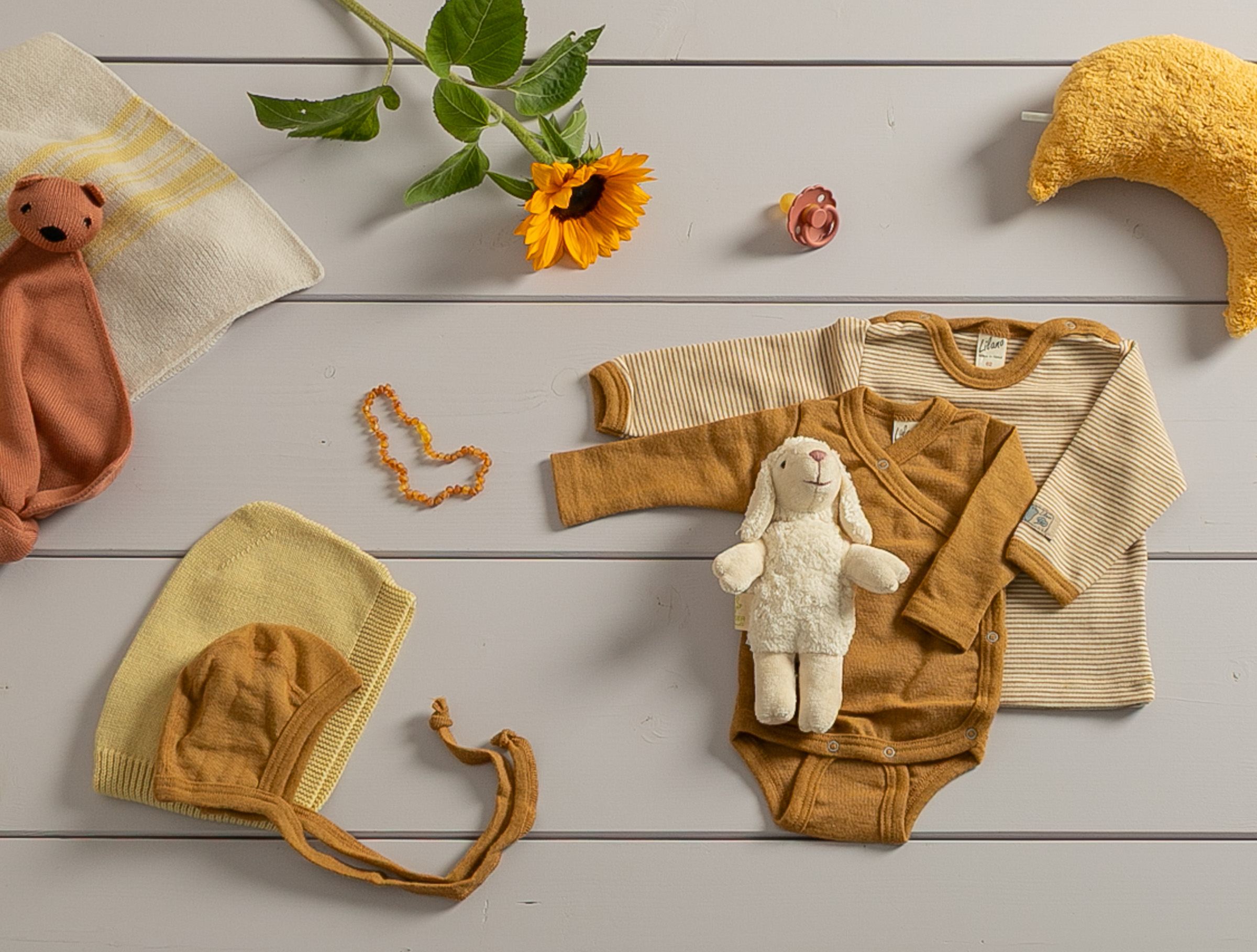 Babykleidung aus Wolle Seide von Lilano in gelben Farben liegen auf einem Tisch.