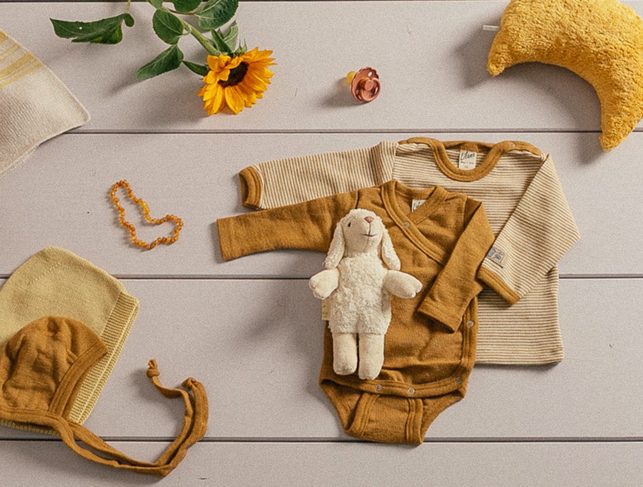 Babykleidung aus Wolle Seide von Lilano in gelben Farben liegen auf einem Tisch.