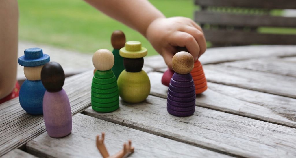 Kleinkind spielt mit Figuren aus Holz.