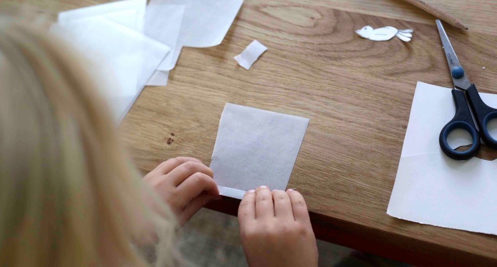 Ein Kind faltet das Transparentpapier.